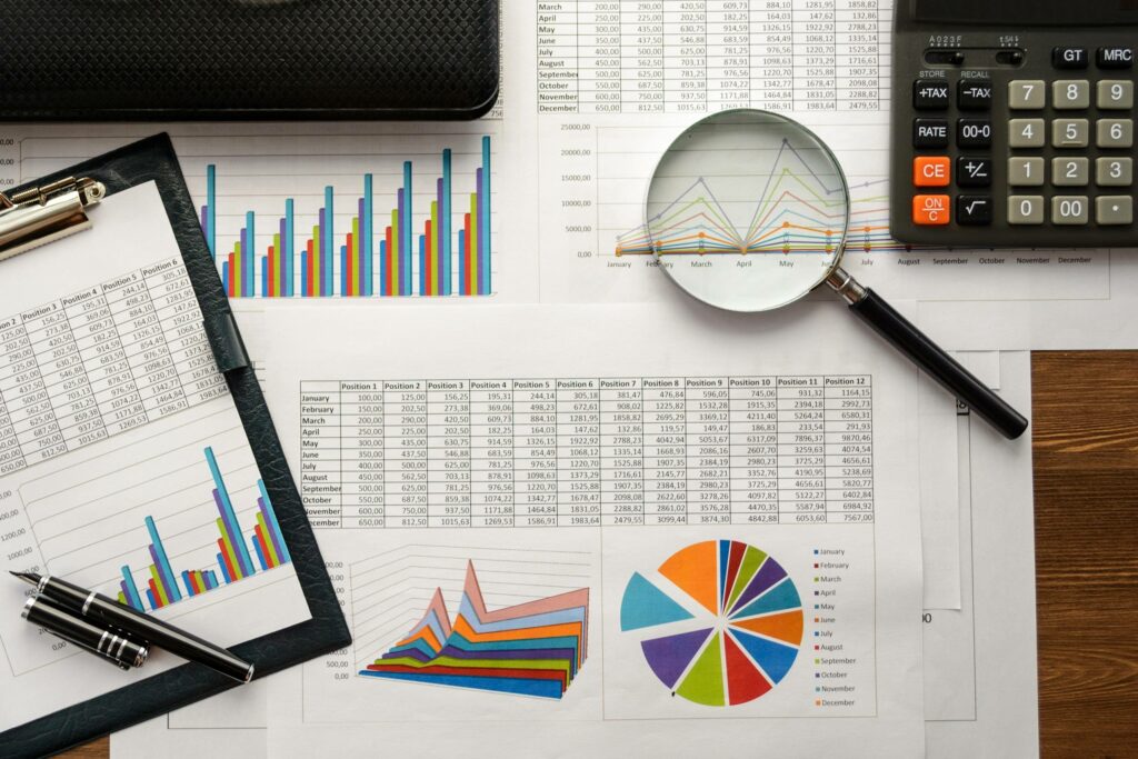 A magnifying glass showing graphs and tables representing the analysis of market data, the evolution of demand and the detection of opportunities linked to emerging technologies.