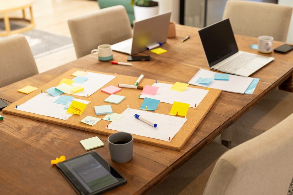 Two computers on a table surrounded by post-it notes, symbolising collaborative thinking and tailor-made economic modelling for strategic issues.